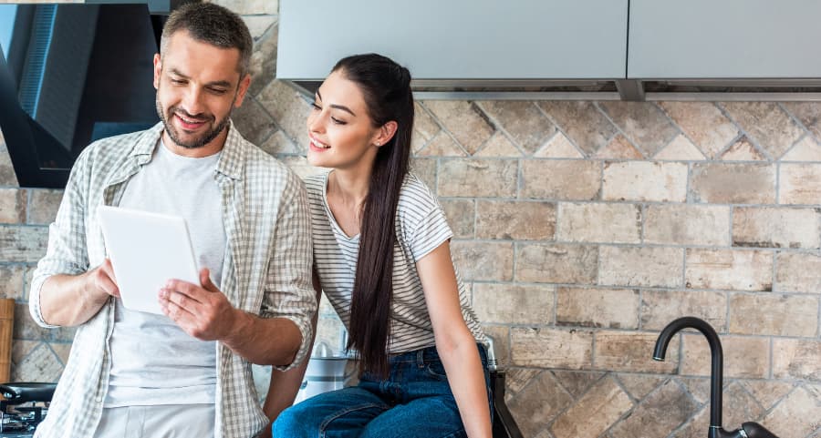 Homeowners using a tablet together in the kitchen to manage smart home